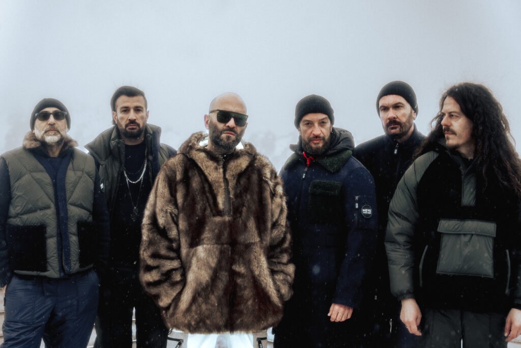 La band Negramaro in primo piano, uno accanto all'altro. Lo sfondo è bianco, come fosse nebbia. Il frontman Giuliano Sangiorgi indossa una pelliccia e gli occhiali da sole.