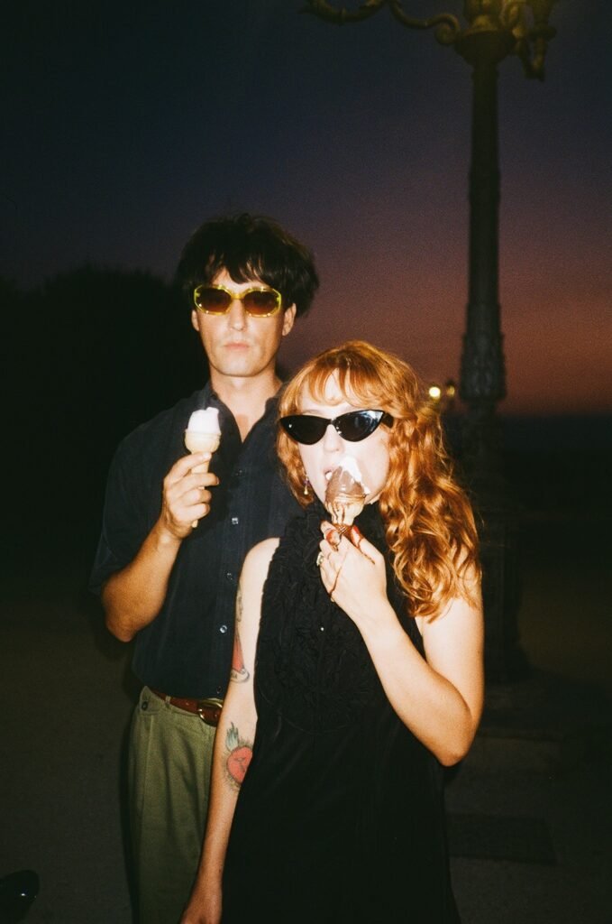 Colombre e Maria Antonietta al crepuscolo, vestiti di nero, con gli occhiami da sole ed un gelato in mano.